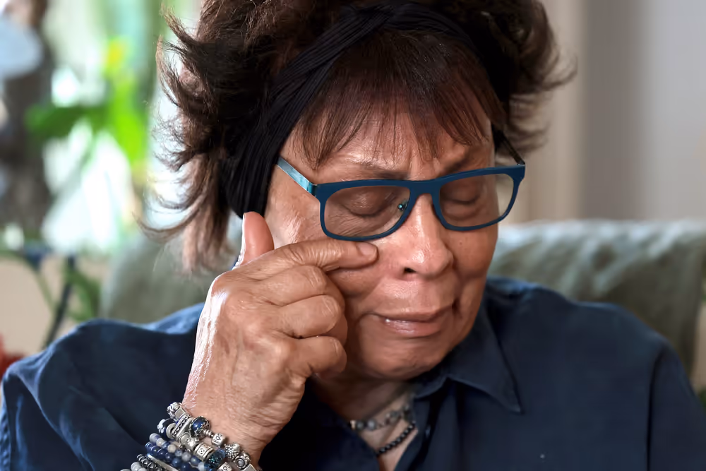 Joyce Thomas torkar tårarna bakom sina glasögon.